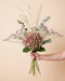 Hand hält den Blumenstrauß Hortensien-Symphonie in der Größe Classic mit altrosa Hortensie, Limonium und feinen Ähren