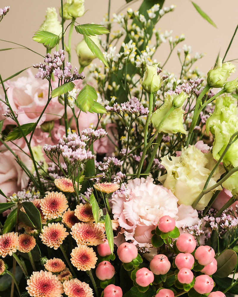 Der handgebundene Blumenstrauß "Morgenlicht" vereint hellrosa Lisianthus, kleine pinke Chrysanthemen, grüne Knospen, zarte weiße Blüten und runde Beeren - perfekt für herbstlichen Zauber in Ihrem Zuhause.
